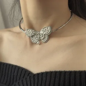 Close-up detail van de zware metalen vlinder choker ketting met een delicate parelhanger.