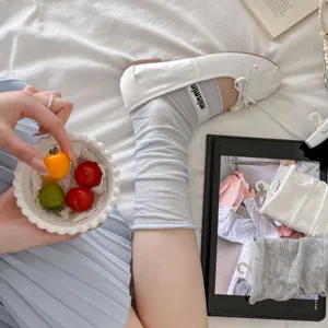 Graue Scrunch-Socken kombiniert mit weißen Ballerinas im schicken Beinstulpen-Stil für Sommer.
