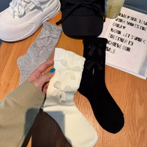 Detailed view of women's mid-calf socks featuring delicate ribbon bows and hollow design.