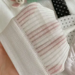 Close-up detail of white knitted stirrup leg warmers, breathable vertical stripe sheer fabric.