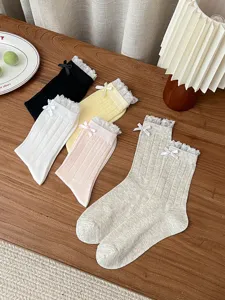 Detailed view of women's mesh mid-calf socks with delicate lace trim and sweet bows, spring summer.