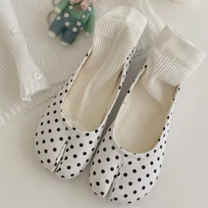 Close-up of white polka dot split-toe stirrup socks with cozy ribbed knit texture.