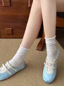 Weisse Lochmuster-Wadensocken kombiniert mit hellblauen Ballett-Flats im Nahbereich.