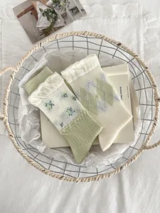 Detail view of women knit mid socks with floral and argyle patterns in fresh green and white tones.