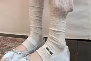 Close-up detail of women stacked leg warmers paired with stylish ballet flat shoes.