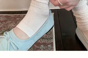Close-up detail of white lace mesh crew socks paired with light blue flat ballet shoes.