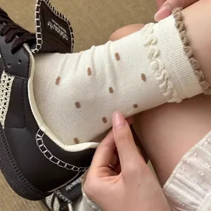 Detailed shot of cute women's white polka dot ruffle mid tube socks showing texture.