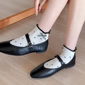 Close-up detail of cute white polka dot socks with bows paired with classic black Mary Jane shoes.