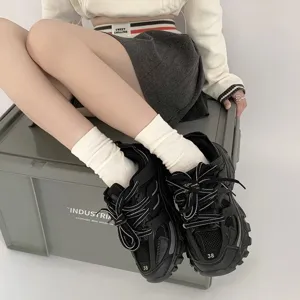 Detailansicht von weißen Damen-Stapelsocken kombiniert mit schwarzen klobigen Schuhen.
