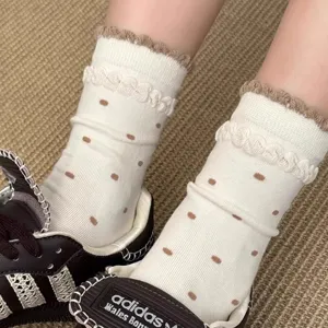 Close-up detail of white vintage polka dot mid-tube socks with brown lace trim and knit cuff.