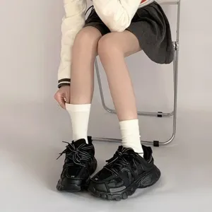 Nahaufnahme von weißen mittelhohen Scrunch-Socken kombiniert mit stylischen Sneakers.