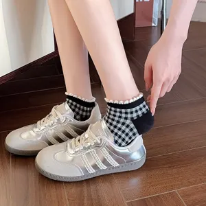 Close-up detail of black and white plaid socks with cute white lace ruffles for women daily.