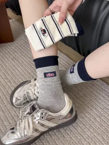 Detail view of women's striped crew socks with cute cartoon sheep embroidery design.