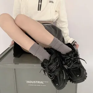 Nahaufnahme von trendigen Damen-Mittelsocken kombiniert mit stylischen schwarzen Sneakers.