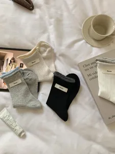 Detailansicht bequemer Baumwoll-Mittelrohrsocken mit vertikalen Streifen und schicken Etiketten.