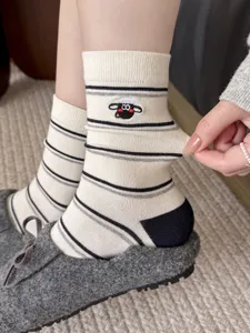 Close-up detail shot of women cute cartoon sheep embroidery striped cotton mid-tube socks.