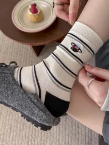 Close-up detail of women's autumn winter cute sheep embroidered striped mid-calf cotton socks.
