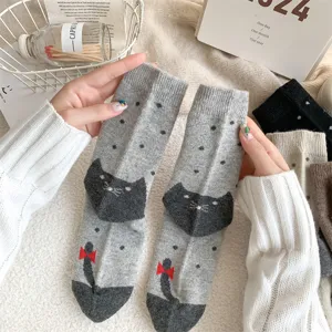 Nahaufnahme dicker Wintersocken mit süßem schwarzem Katzen- und rotem Schleifendesign.