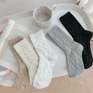 Close-up detail of cozy twisted cable knit socks in assorted neutral colors displayed nicely.