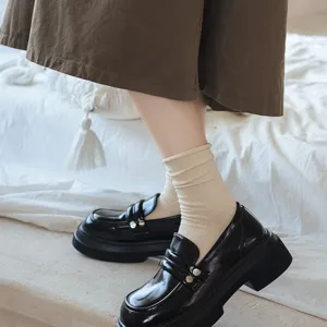 Close-up detail of women casual crew slouch socks paired with black chunky loafers.