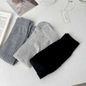 Ribbed knit mid-calf sock details in dark grey, light grey, and black, soft textured flat lay view.