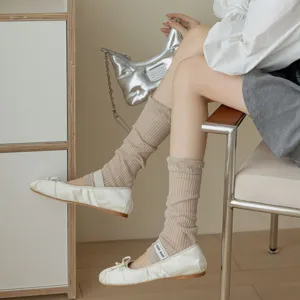 Detailed view of women's white satin ballet flats with strap and cozy beige ribbed socks.
