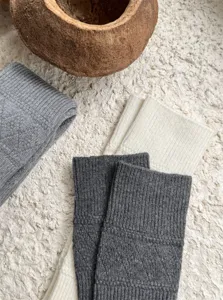 Wool knit over-the-knee socks detail shot, showing soft ribbed texture and hollow-out diamond pattern.