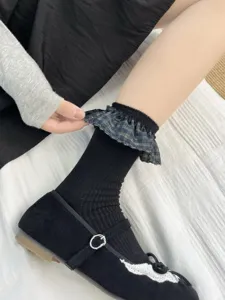 Gros plan sur une chaussette noire côtelée à revers à volants écossais et texture douce.