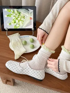 Detailed view of sweet style crew socks with ruffled green edge paired with polka dot shoes.