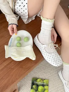 Detail shot of women's white mid-tube socks with delicate lace and cute green ruffled cuffs.