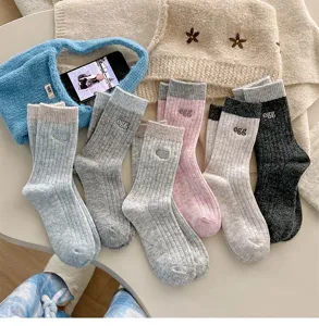 Gemütliche Rippstrick-Wollsocken im Detail mit süßer Stickerei und Kontrastbündchen für Winter.