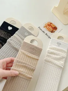 Close-up detail of sweet Japanese style mesh mid-tube socks with cute heart embroidery.