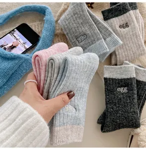 Detailansicht kuscheliger Wollmisch-Wintersocken mit süßer Buchstabenstickerei und Rippstruktur.