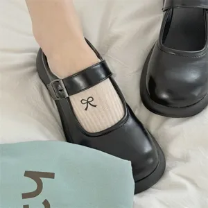 Nahaufnahme von süßen Schleifen-Stickerei-Socken kombiniert mit schwarzen Mary Jane Schuhen.