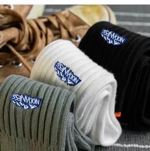 Detailaufnahme dicker Rippstrümpfe mit besticktem Logo-Patch in verschiedenen Farben.