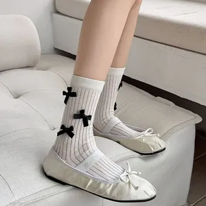Detailed view of women's white mid-calf socks featuring cute black bows and ribbed texture.
