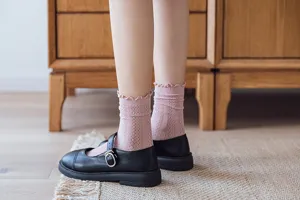 Detailansicht rosa Rüschen Mesh Wadenstrümpfe kombiniert mit klassischen schwarzen Mary Jane Schuhen.