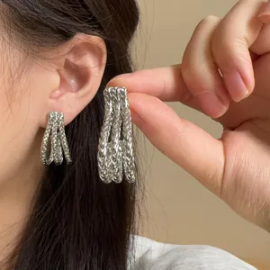 Close-up detail showcasing the braided texture and J-shape of the silver-tone metal earrings.