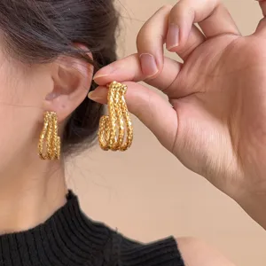 Metal braided J-shaped gold plated earrings detail view, showing elegant fashion style.
