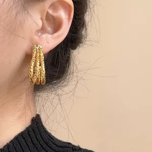 Detailed close-up view of multi-strand textured gold-plated J-shaped hoop earrings.