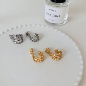 Metal textured J-shaped hoop earrings detail, featuring gold and silver fashion jewelry design.