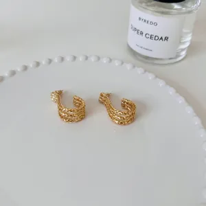 Gold multi-strand textured J-shaped hoop earrings, detailed close-up shot metal craft.