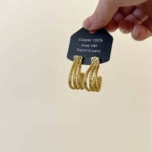 Gold braided J-shaped copper hoop earrings, textured metallic dangle ear jewelry.
