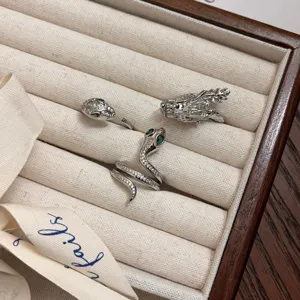 Vista detallada del juego de anillos de dragón y serpiente de plata con piedras brillantes.