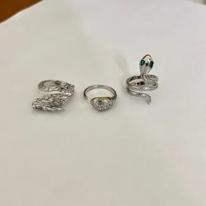 Primer plano detallado de anillos únicos de dragón y serpiente con piedras de circonita.