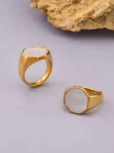 Gedetailleerd overzicht van een geometrische vergulde ring met witte schelp inleg.
