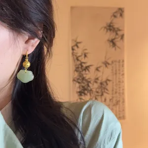 Neo-Chinese style handmade green jade ruyi lock and gold filigree bead earrings detail.