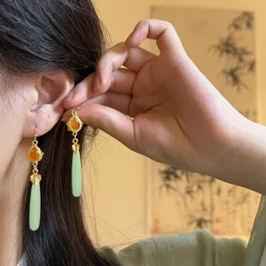 Detailed shot of neo-Chinese retro green drop tassel earrings, showcasing exquisite metal.