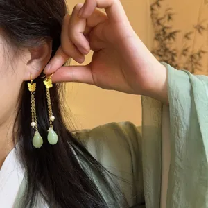 Close-up detail shot of traditional Chinese style butterfly and jade drop dangle earrings.