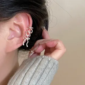 Detalle de un pendiente de oreja con lazo plateado, diseño elegante sin perforación.